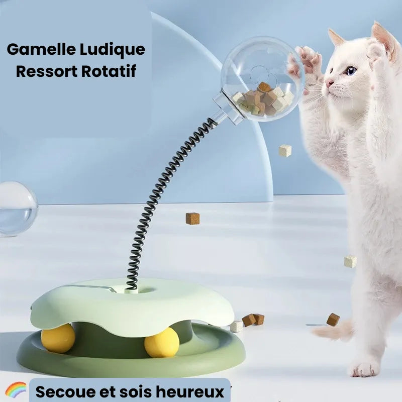 Chat blanc qui joue avec une Gamelle ludique chat ressort rotatif vert
