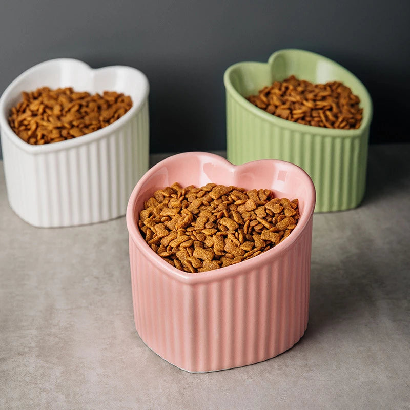 Gamelle chat surélevée forme coeur blanc, rose et vert pomme rempli de croquettes